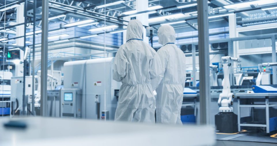 Technicians in cleanroom suits walking through a semiconductor facility